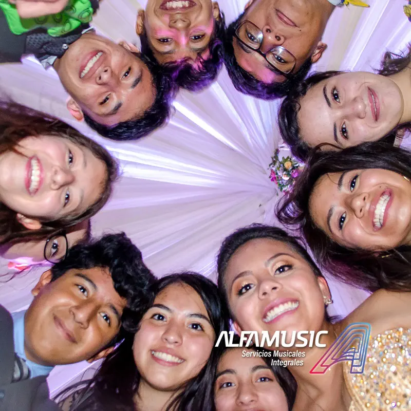 Ximena en sus XV super divertida haciendo una rueda con sus mejores amigos. La foto está tomada desde el piso enmedio de ellos