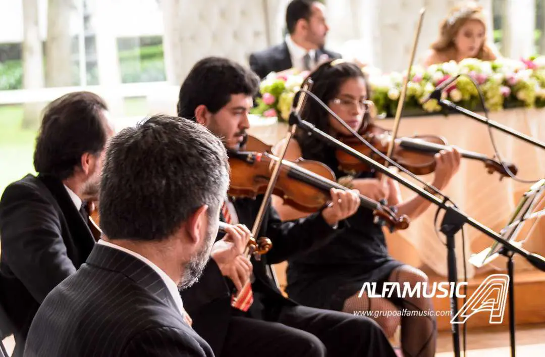 Ensamble Dalí presentándose en una comida. Se ven tres violines y al fondo la mesa principal con los novios