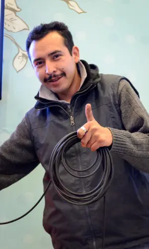 Gustavo Bautista saludando mientras sostiene un rollo de cable, durante la instalación de un evento del grupo versátil Alfamusic