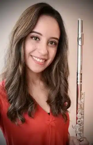 Flautista Patti Rodriguez, sonríe sosteniendo su instrumento mientras participa con el ensamble Dalí de Alfamusic