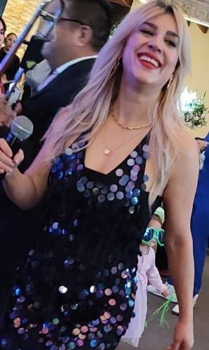 Imagen de una mujer sonriendo en un evento musical Alfamusic, vestida con un vestido de lentejuelas.