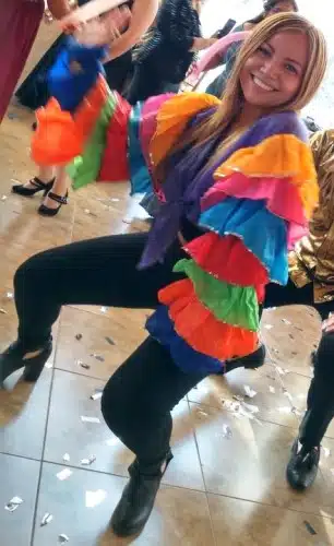 Ximena animadora bailando en la pista, vistiendo ropa negra y vestuario de carnaval