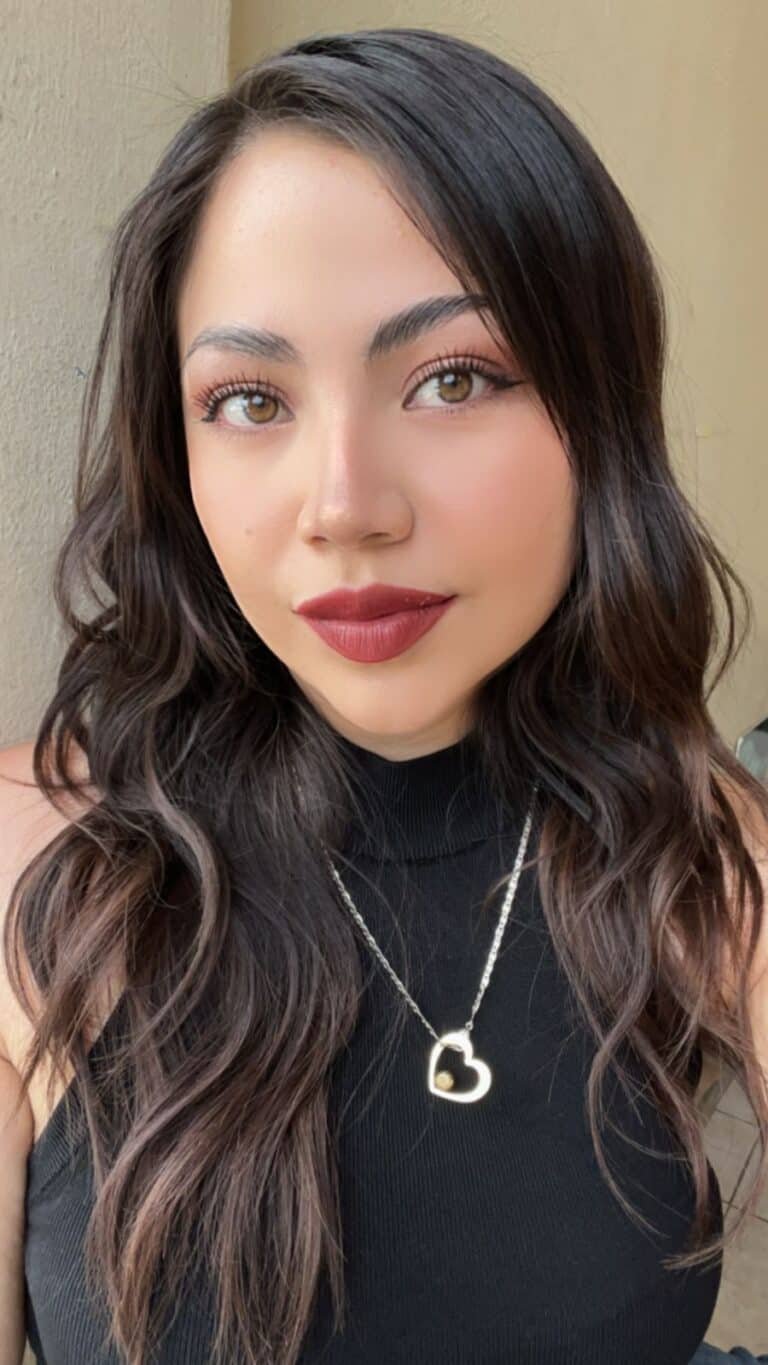 Ximena animadora en retrato con ropa negra y un collar de plata, cabello largo y labios pintados color rojo