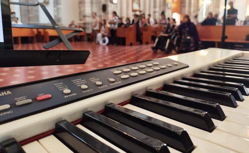 Teclado en concurso musical en Alfamusic, con público disfrutando en el fondo.