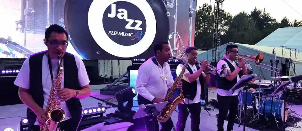 Alfamusic tocando en la Feria de Metepec 2024, banda de jazz en escenario al aire libre.