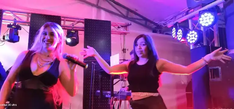 Dos chicas en escenario celebrando XV años de Camila con música y alegría.