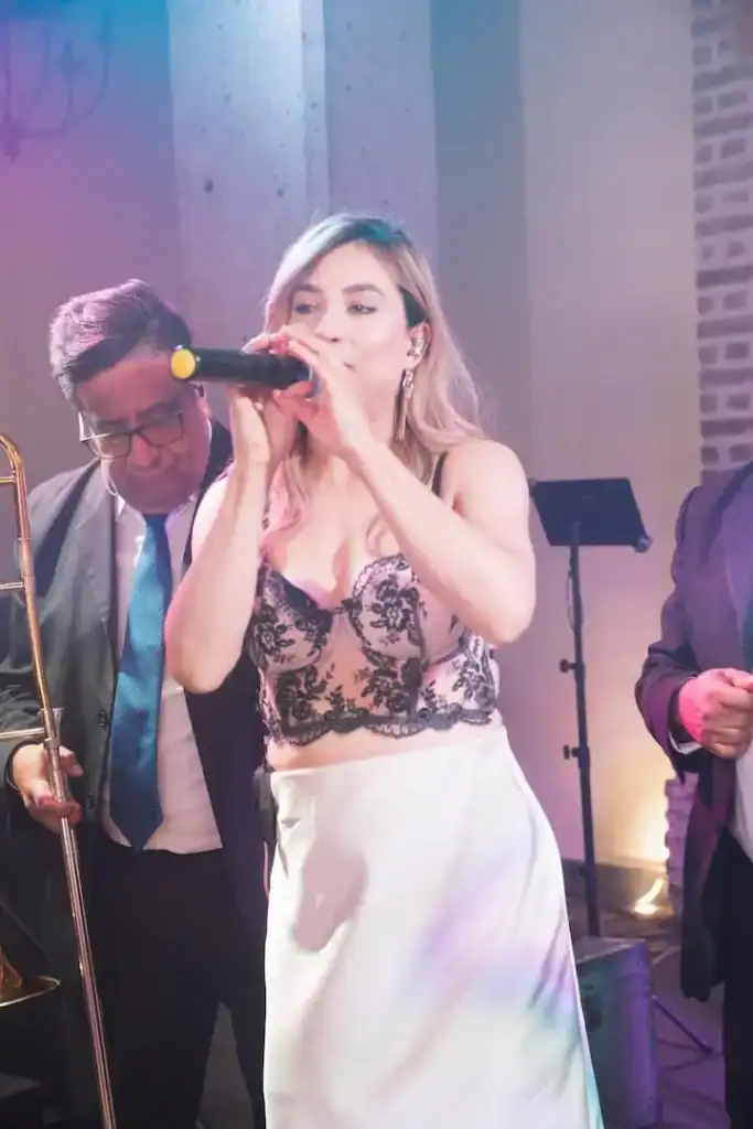 Imagen de una cantante en vivo en la boda de Patti y Braulio, con músicos acompañantes en un evento.
