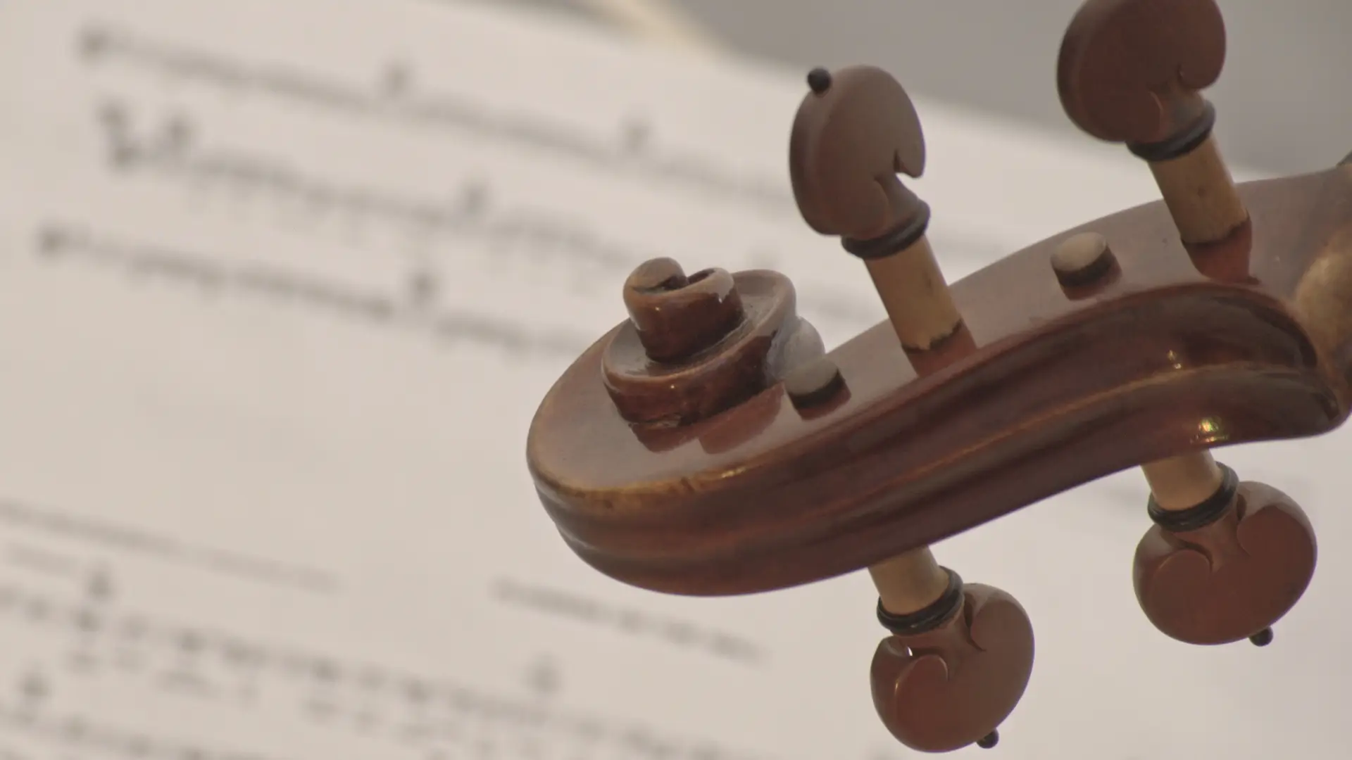 Guitarra clásica de madera con afinadores en primer plano, fondo difuso con notas musicales y partit.